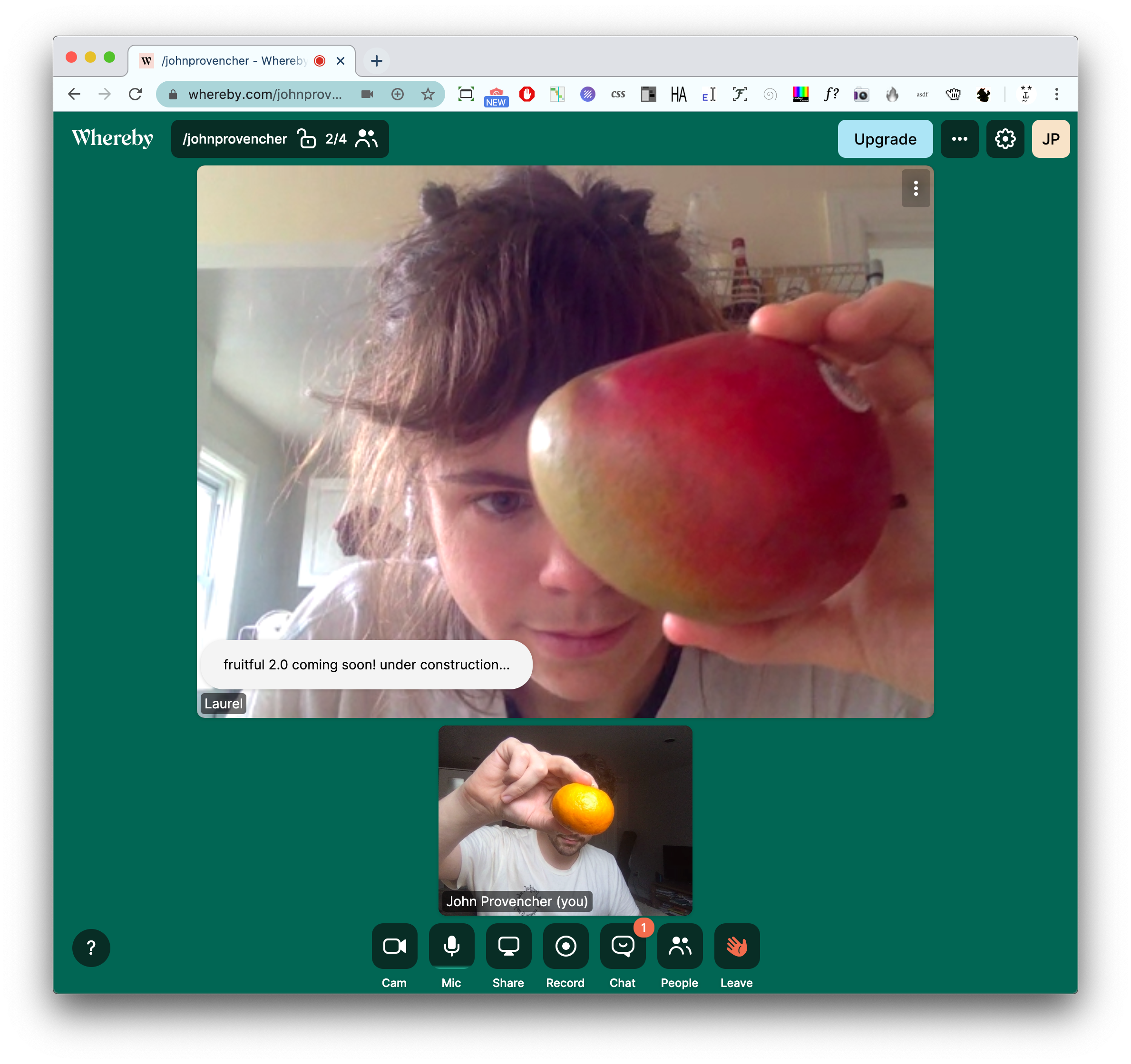 A screenshot of two people video chatting while holding fruits on the Whereby platform. Laurel appears in a larger frame than the other, and she presents a mango. John Provencher is in the smaller frame, and he covers his face with a clementine.