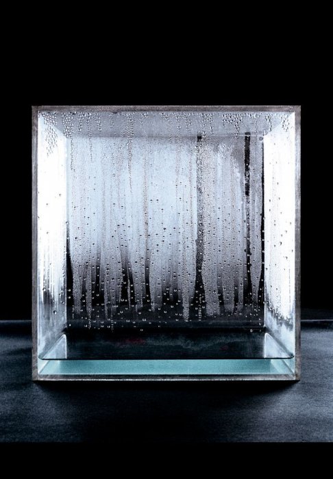 A clear cube against a dark bacgkround, showing droplets of condensation on its walls