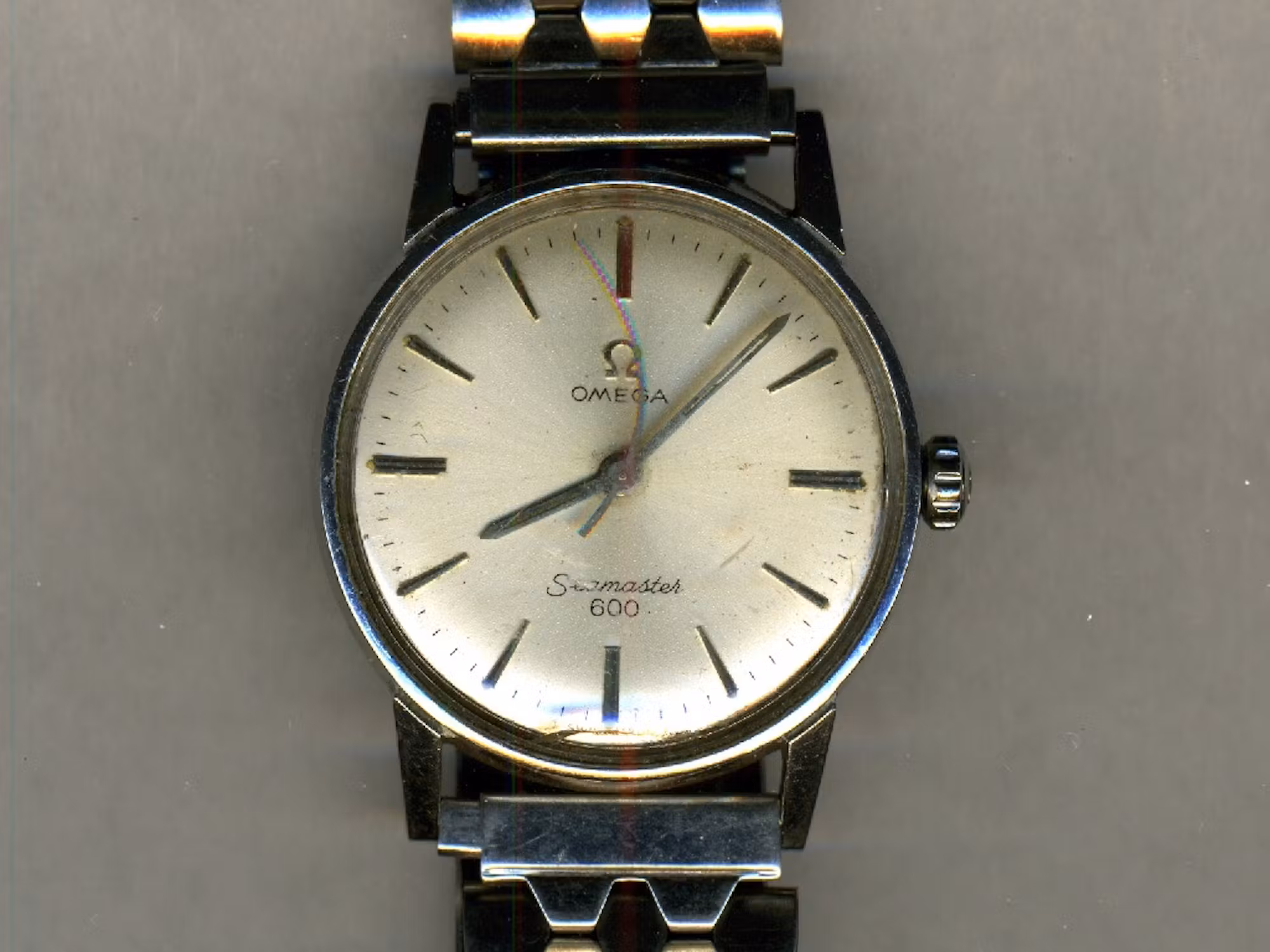 a scan of a silver omega watch set to 8:08, with the second hand arched towards the 12 o'clock point.